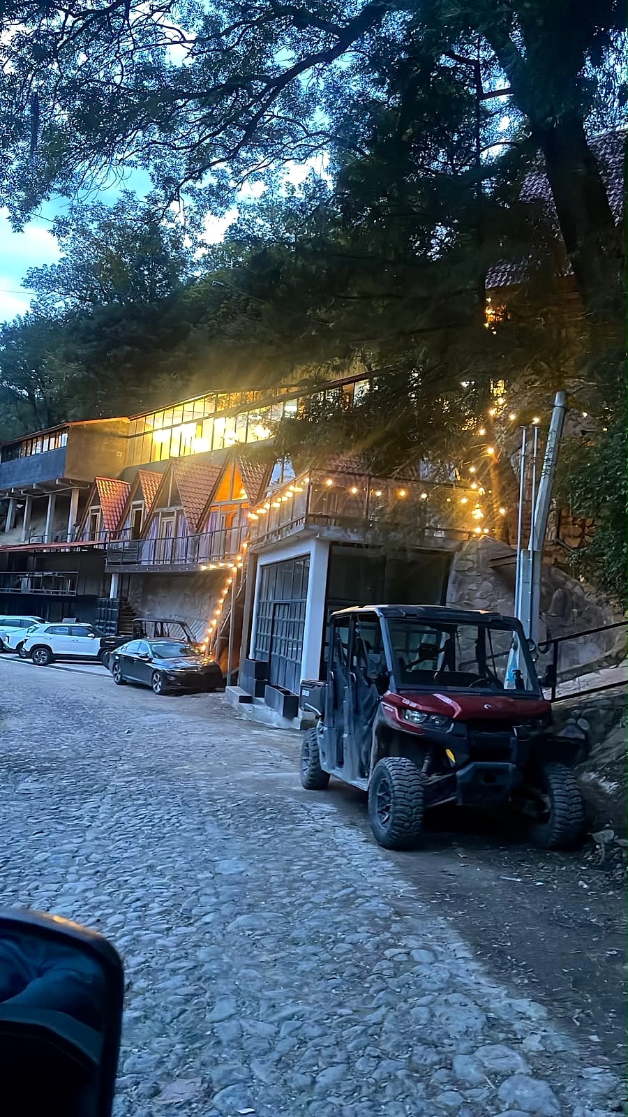 Las cabañas al atardecer con luces cálidas colgantes y un RZR listo para la aventura.